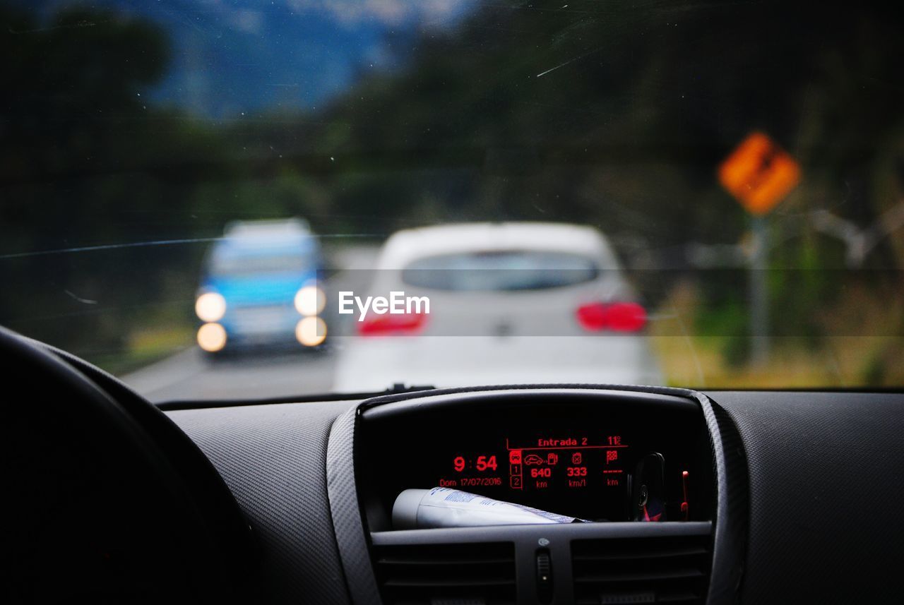 CLOSE-UP OF RED CAR WINDSHIELD ON SIDE-VIEW MIRROR