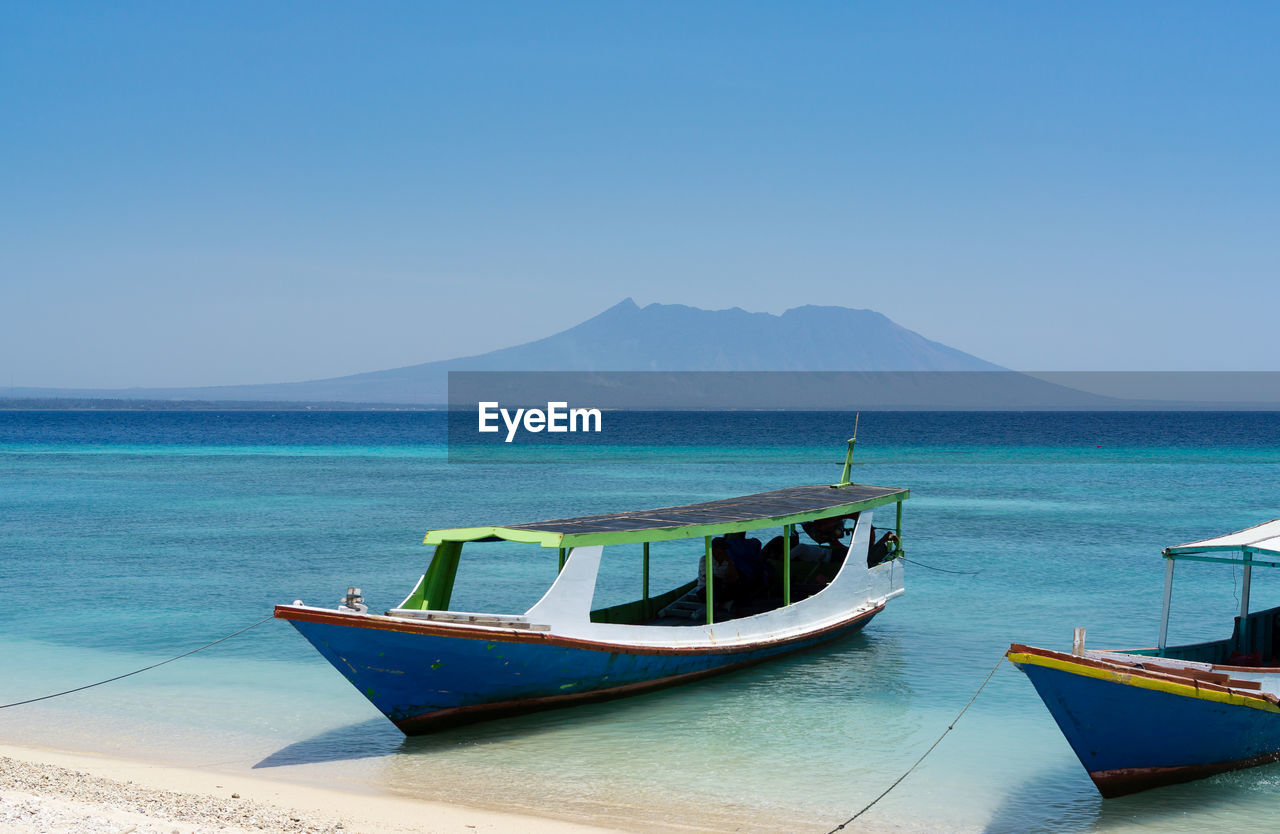 Boat moored on sea against clear sky