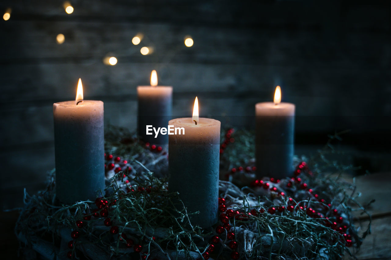 CLOSE-UP OF ILLUMINATED CANDLES AGAINST BLURRED LIGHTS