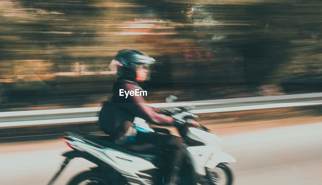 Side view of man riding motorcycle on street