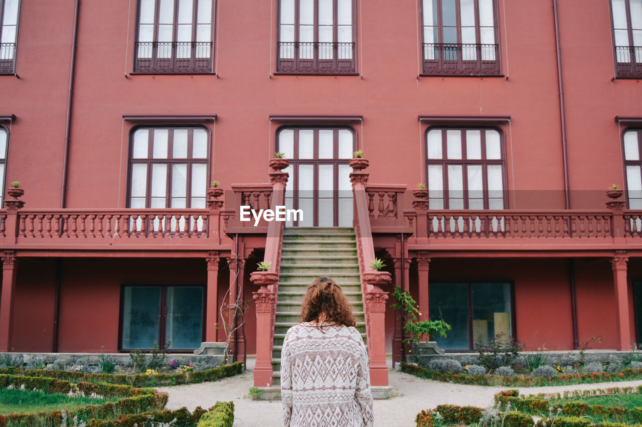 Rear view of woman standing against building