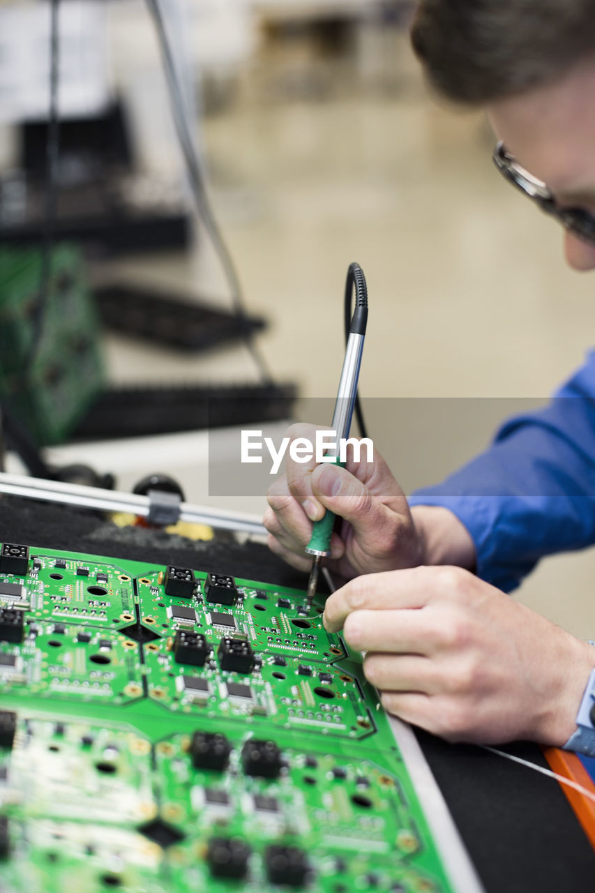 Cropped image of mature male electrician soldering circuit board