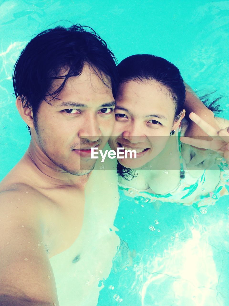 Portrait of smiling couple swimming in pool