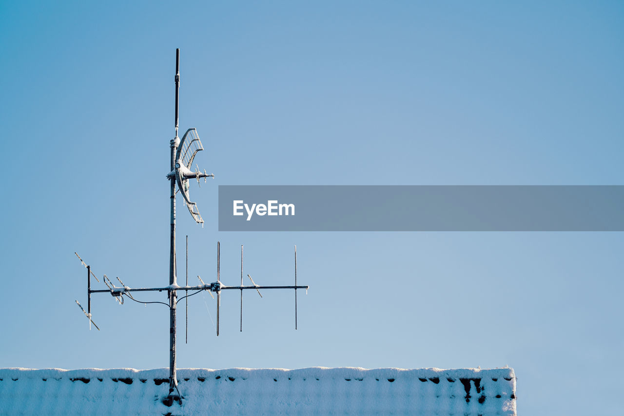 Frozen aerial antenna on snowy roof
