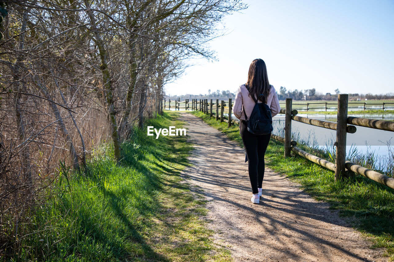 Beautiful woman hiking on a path close to a river back shot person