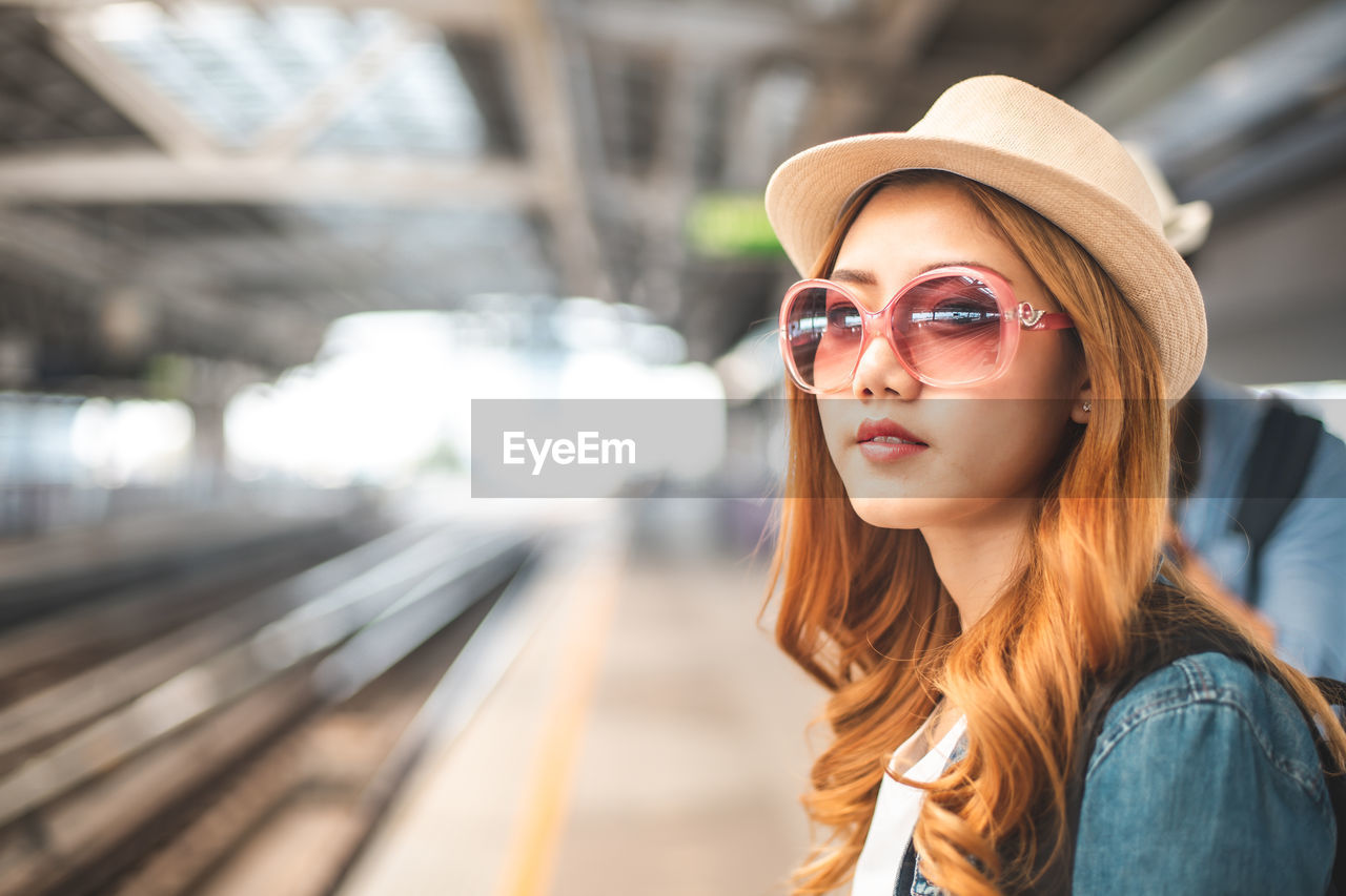 PORTRAIT OF YOUNG WOMAN IN SUNGLASSES AT BUS