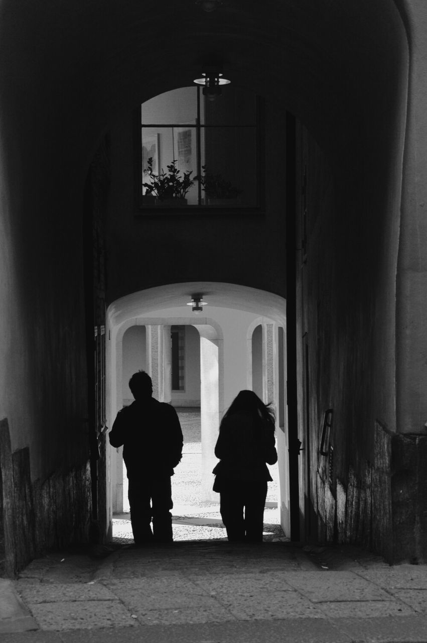 Silhouette couple walking in narrow pathway
