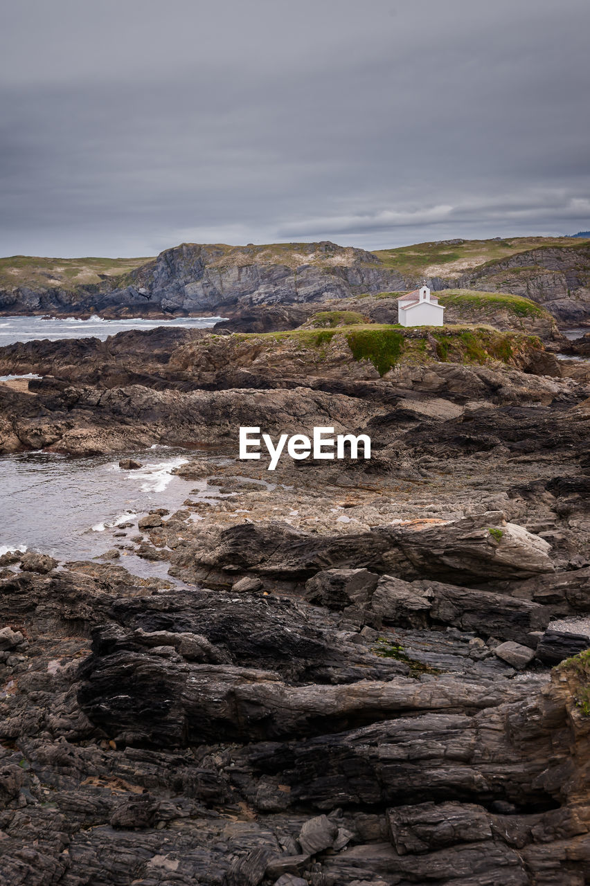 Rock formation on beach against sky