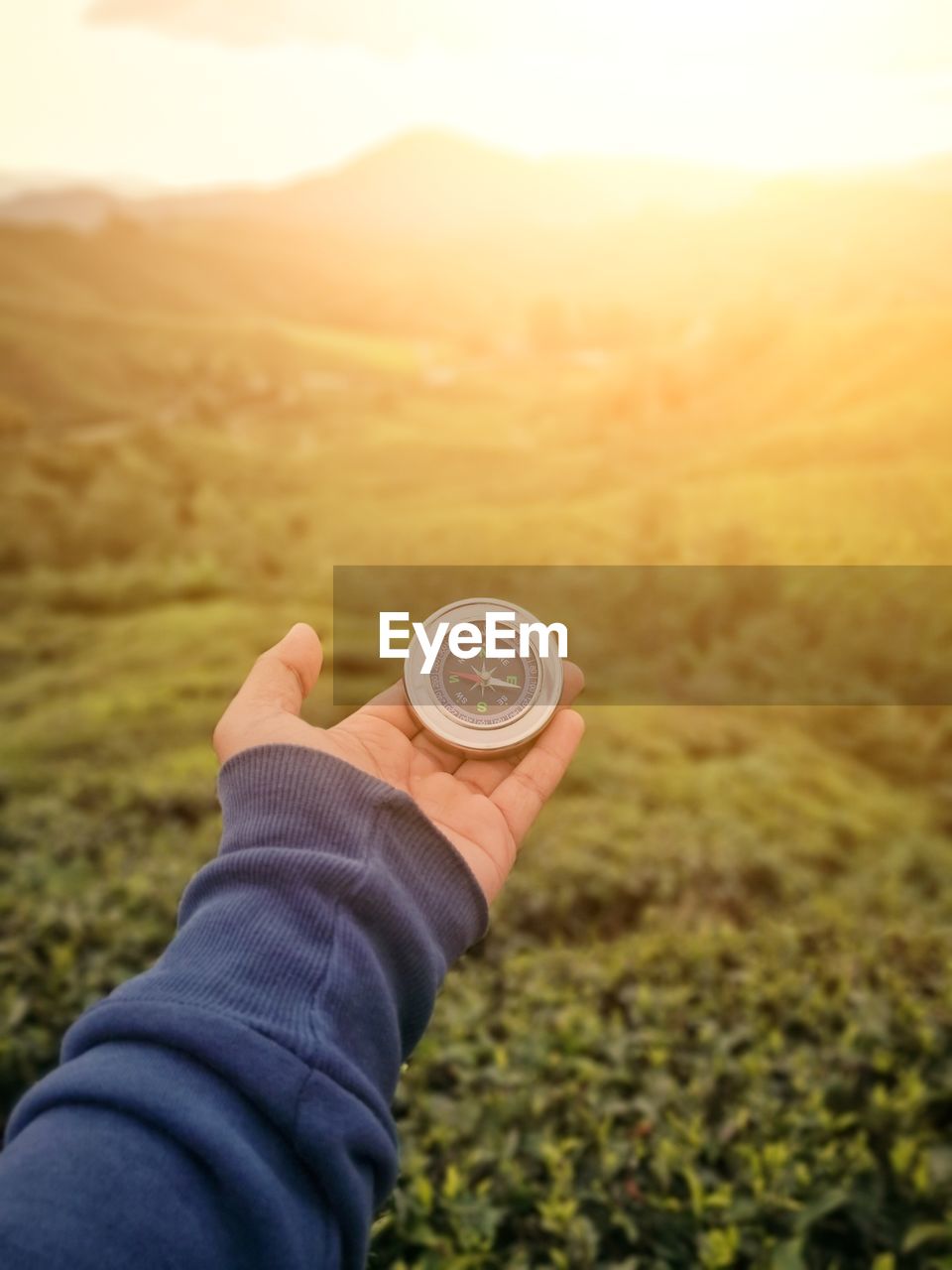 Cropped hand of person holding navigational compass on land