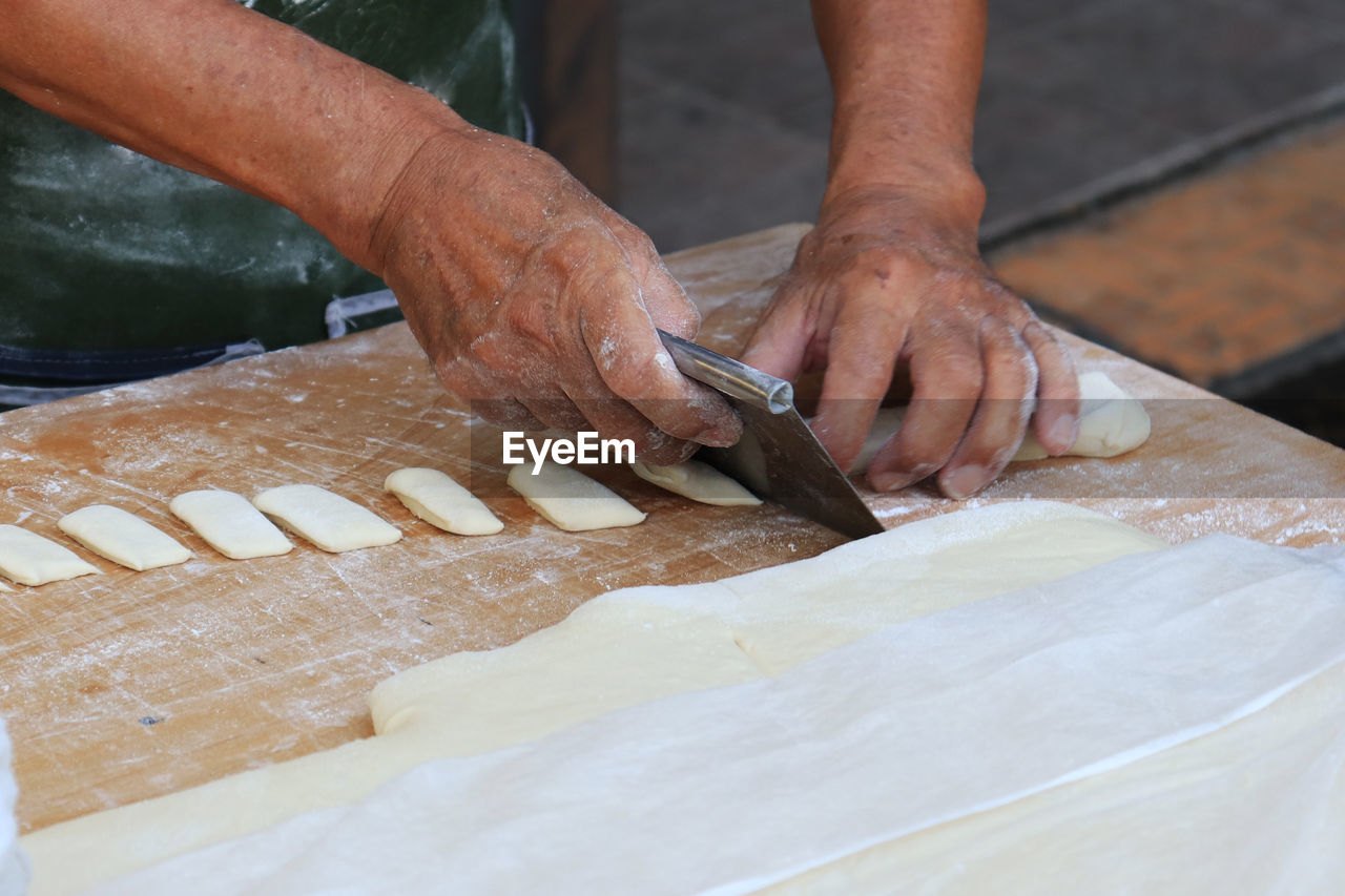 MIDSECTION OF MAN PREPARING FISH IN KITCHEN