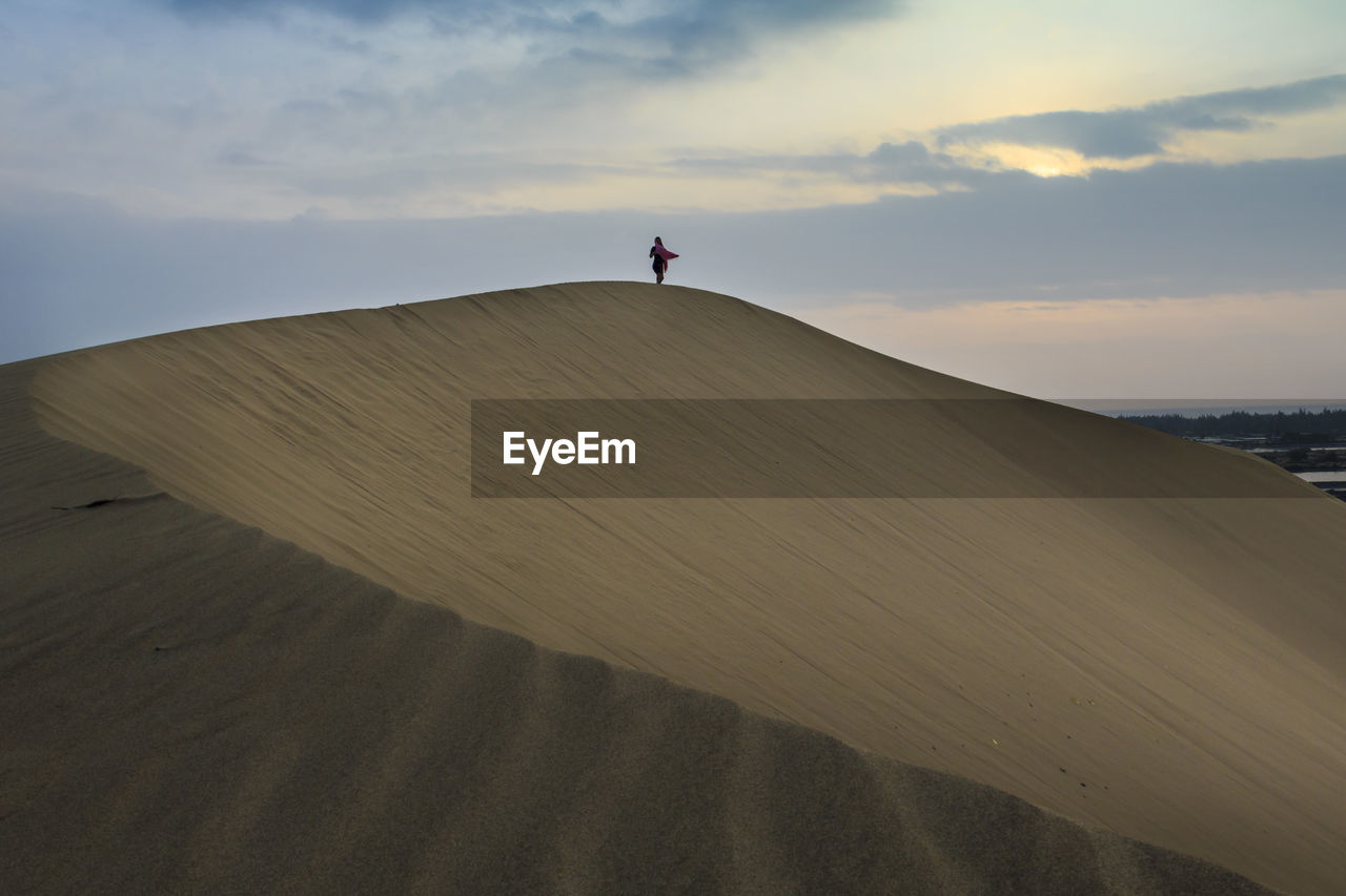 FULL LENGTH OF MAN STANDING ON SAND DUNE