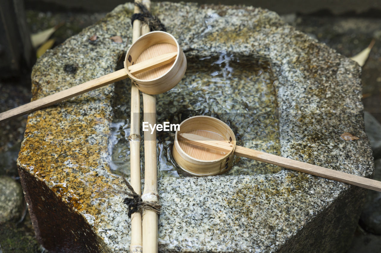 Close view on a japanese temizuya, a purification font, with two bamboo ladles and stone basin.