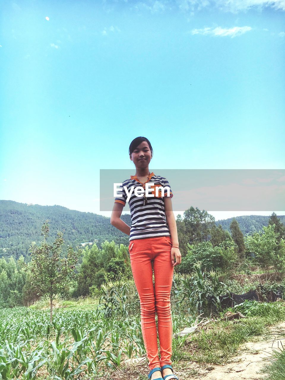 WOMAN STANDING ON MOUNTAIN AGAINST SKY