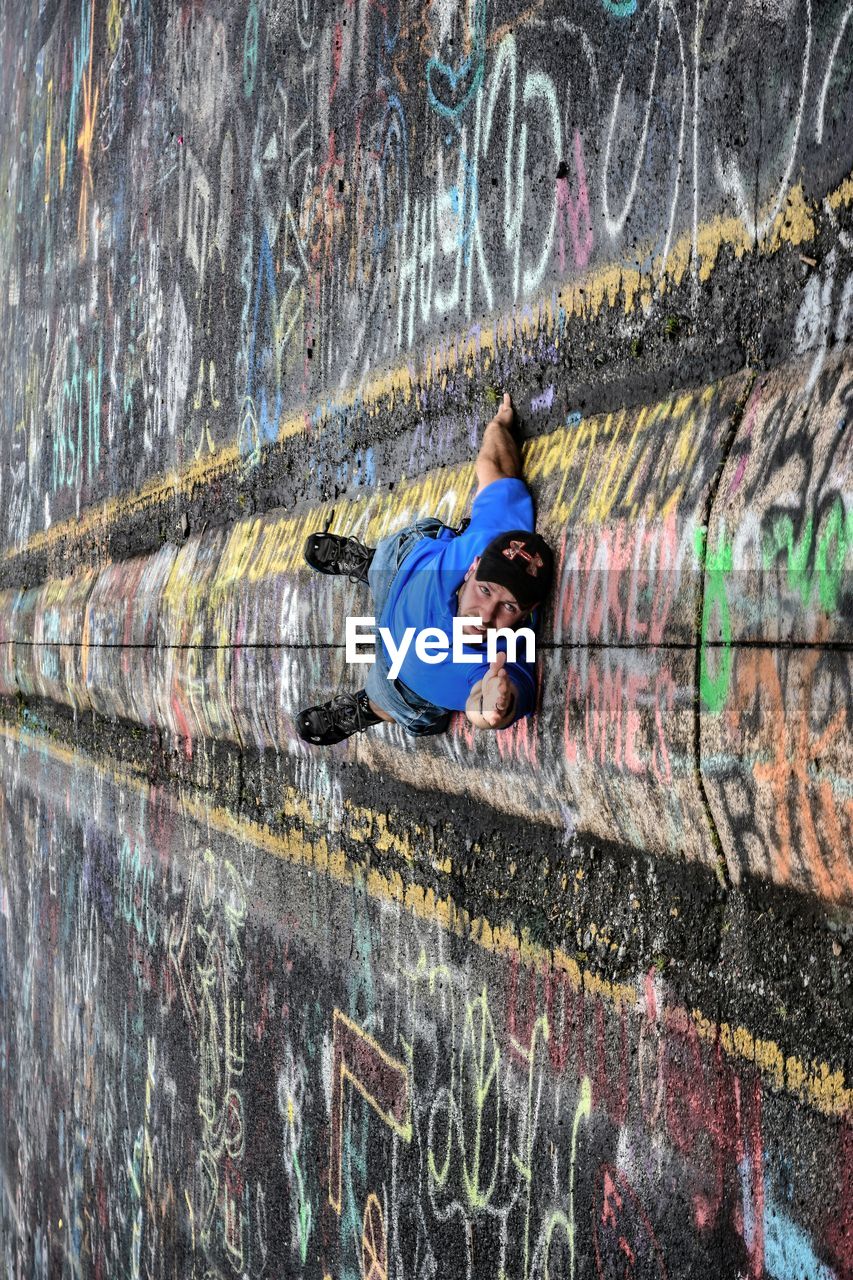 FULL LENGTH OF YOUNG WOMAN STANDING ON WALL