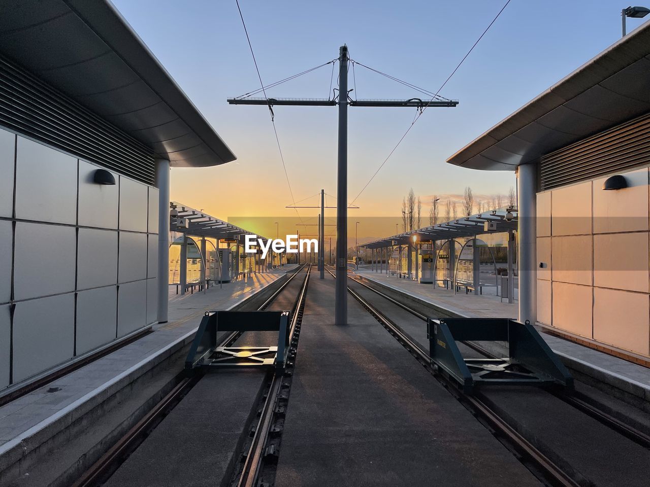 Railroad tracks amidst buildings against sky during sunset