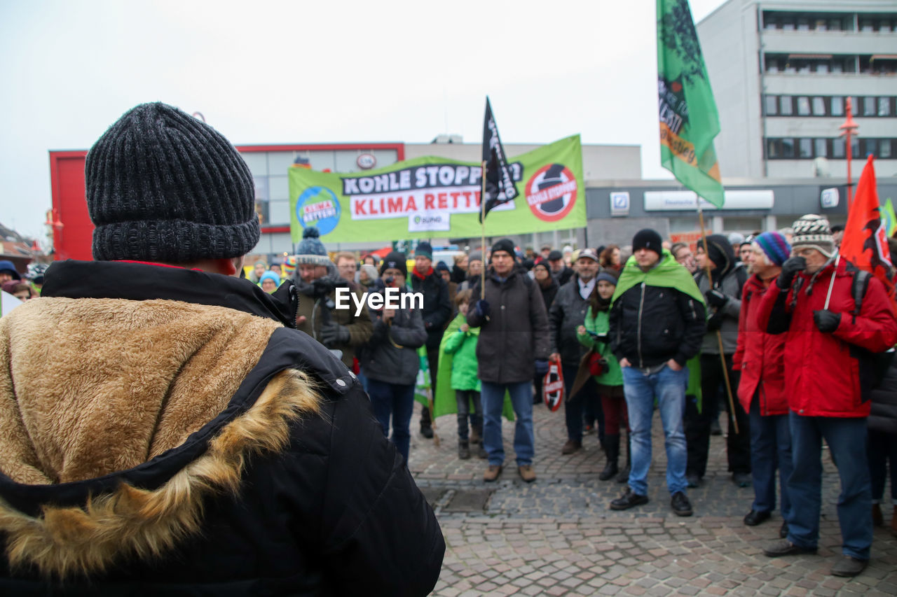 REAR VIEW OF PEOPLE ON STREET AGAINST SKY