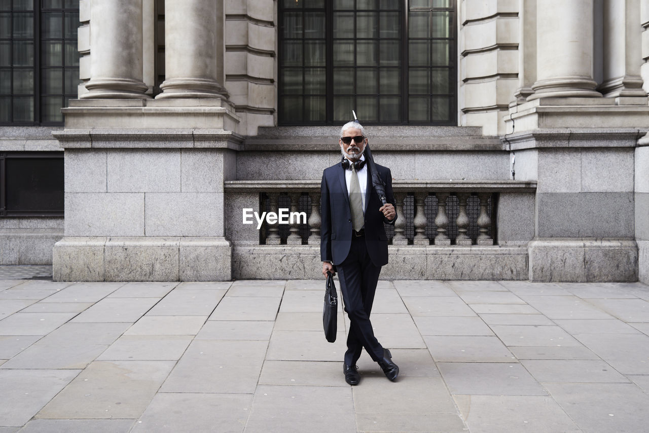 Uk, london, portrait of stylish businessman with sunglasses and umbrella wearing suit and tie