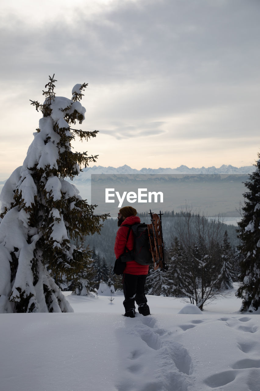 FULL LENGTH REAR VIEW OF MAN STANDING ON SNOW