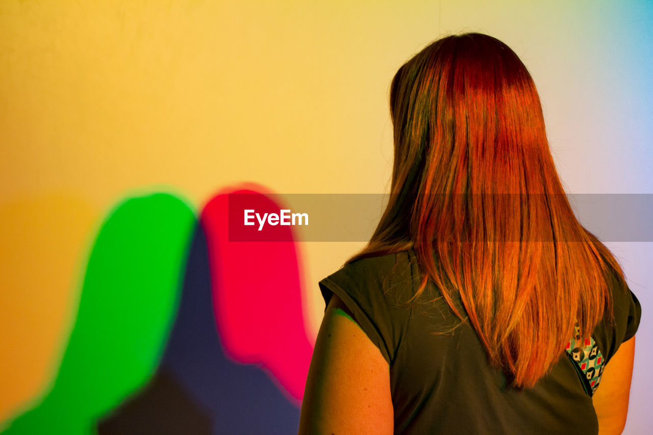 Colorful dual shadows of woman on wall