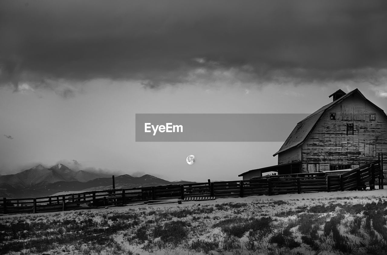 Low angle view of barn against cloudy sky at dusk