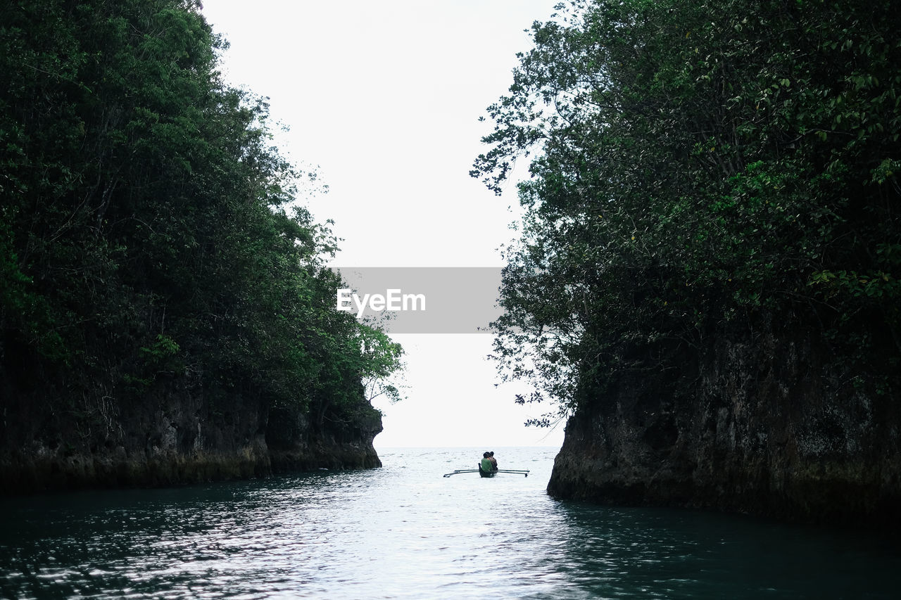 Mid distance of people in boat on lake amidst rocks