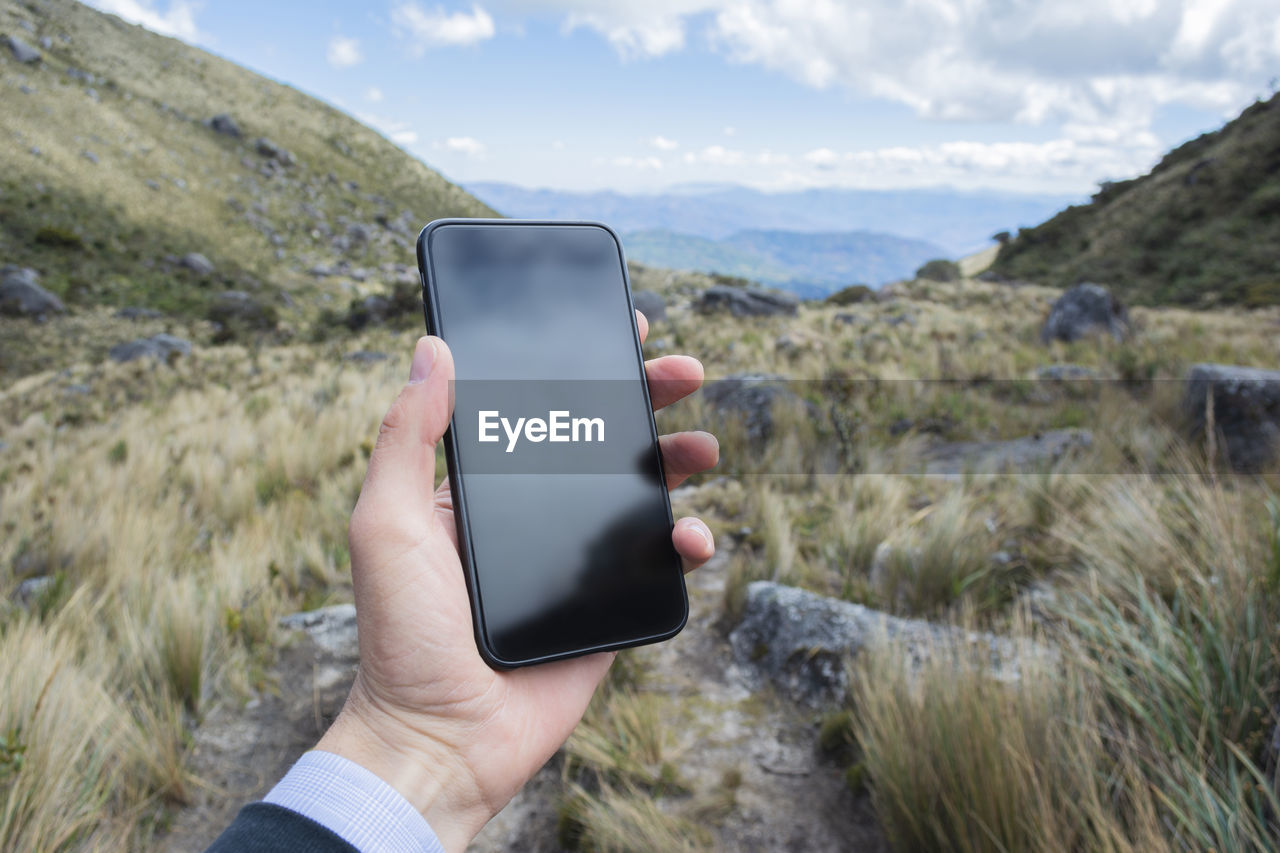 Midsection of person using mobile phone in mountains