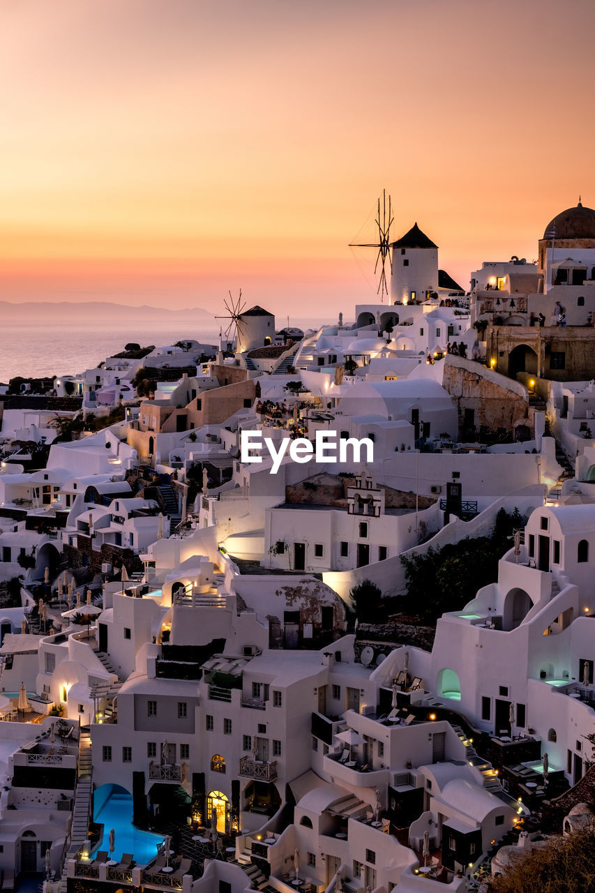 HIGH ANGLE VIEW OF TOWNSCAPE BY SEA DURING SUNSET