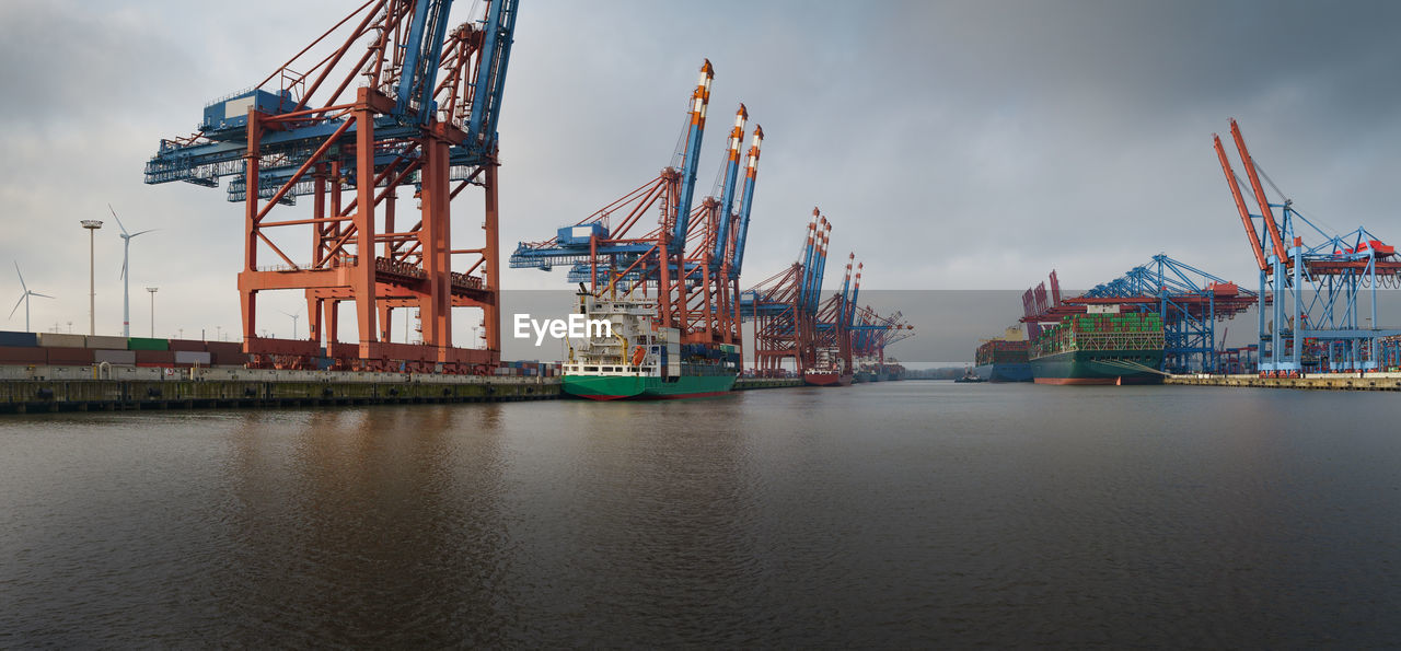 Cranes at commercial dock against sky