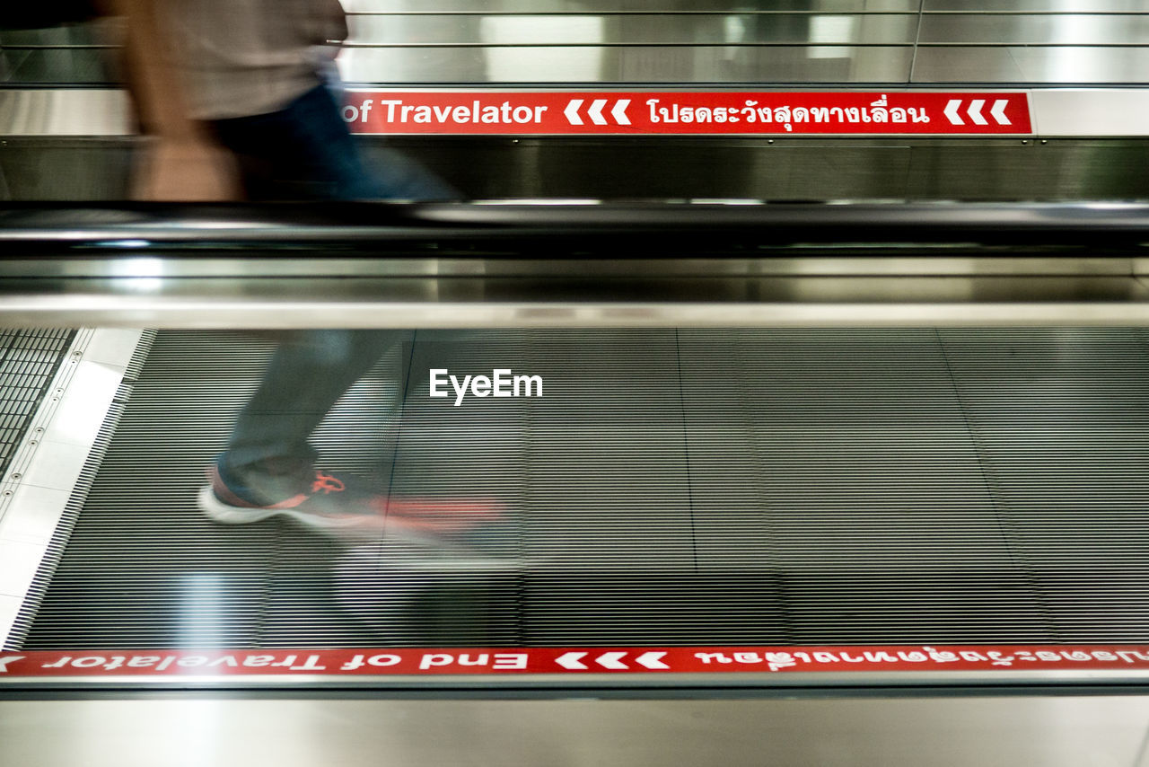 Low section of blurred man on escalator at suvarnabhumi airport