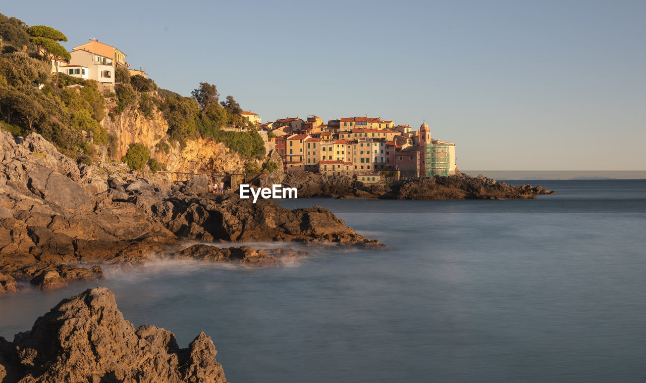 Buildings by sea against clear sky