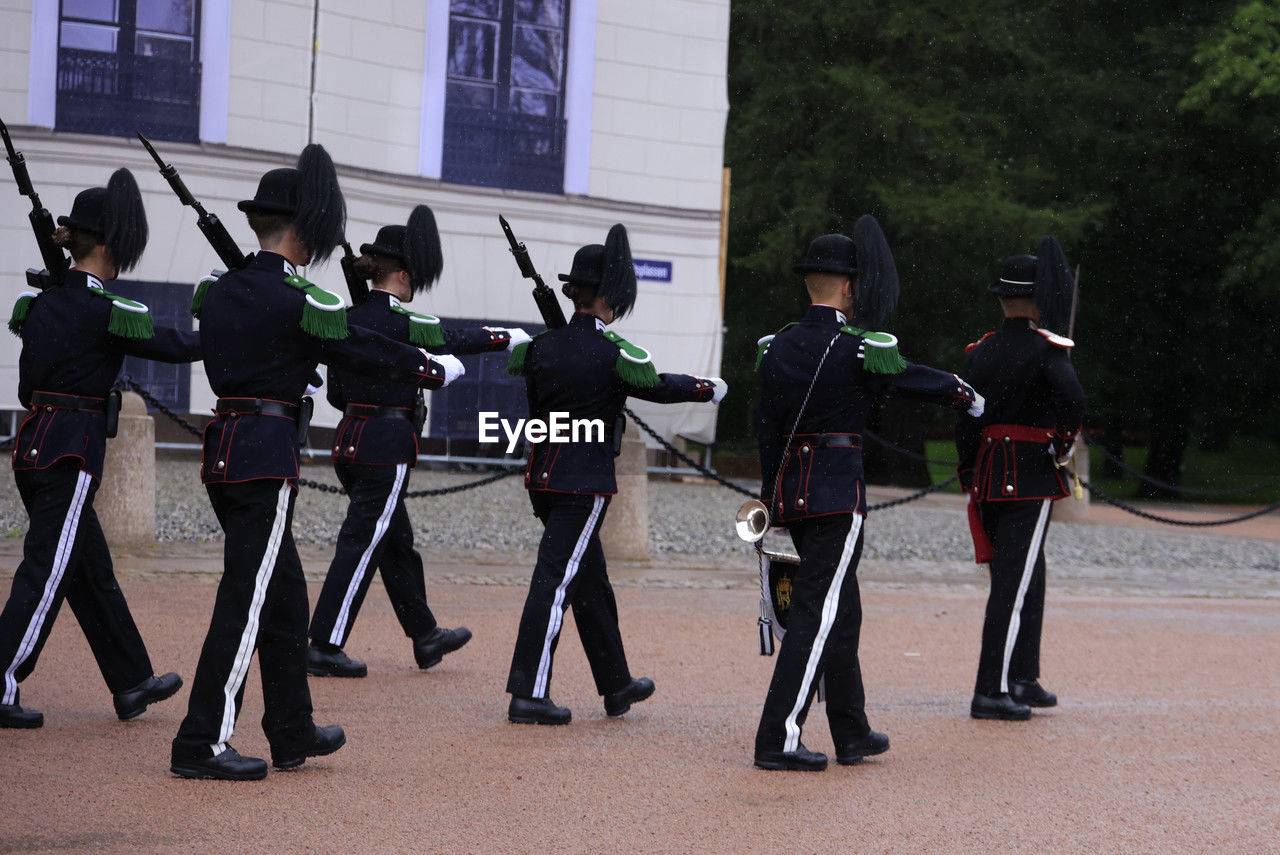 group of people, government, marching, uniform, clothing, architecture, military, person, full length, security, weapon, law, men, armed forces, protection, city, military uniform