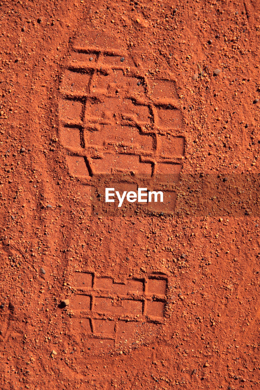 Close-up of shoeprint on sandy field