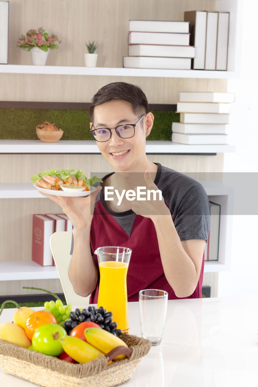 PORTRAIT OF SMILING YOUNG MAN HAVING FOOD IN GLASS