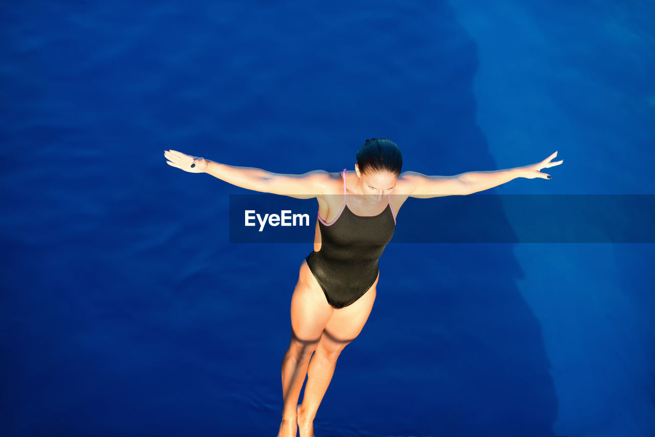 High angle view of woman with arms outstretched diving into swimming pool