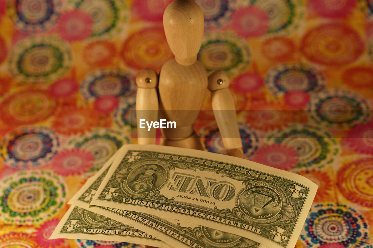 Wooden figurine with currencies on designed paper