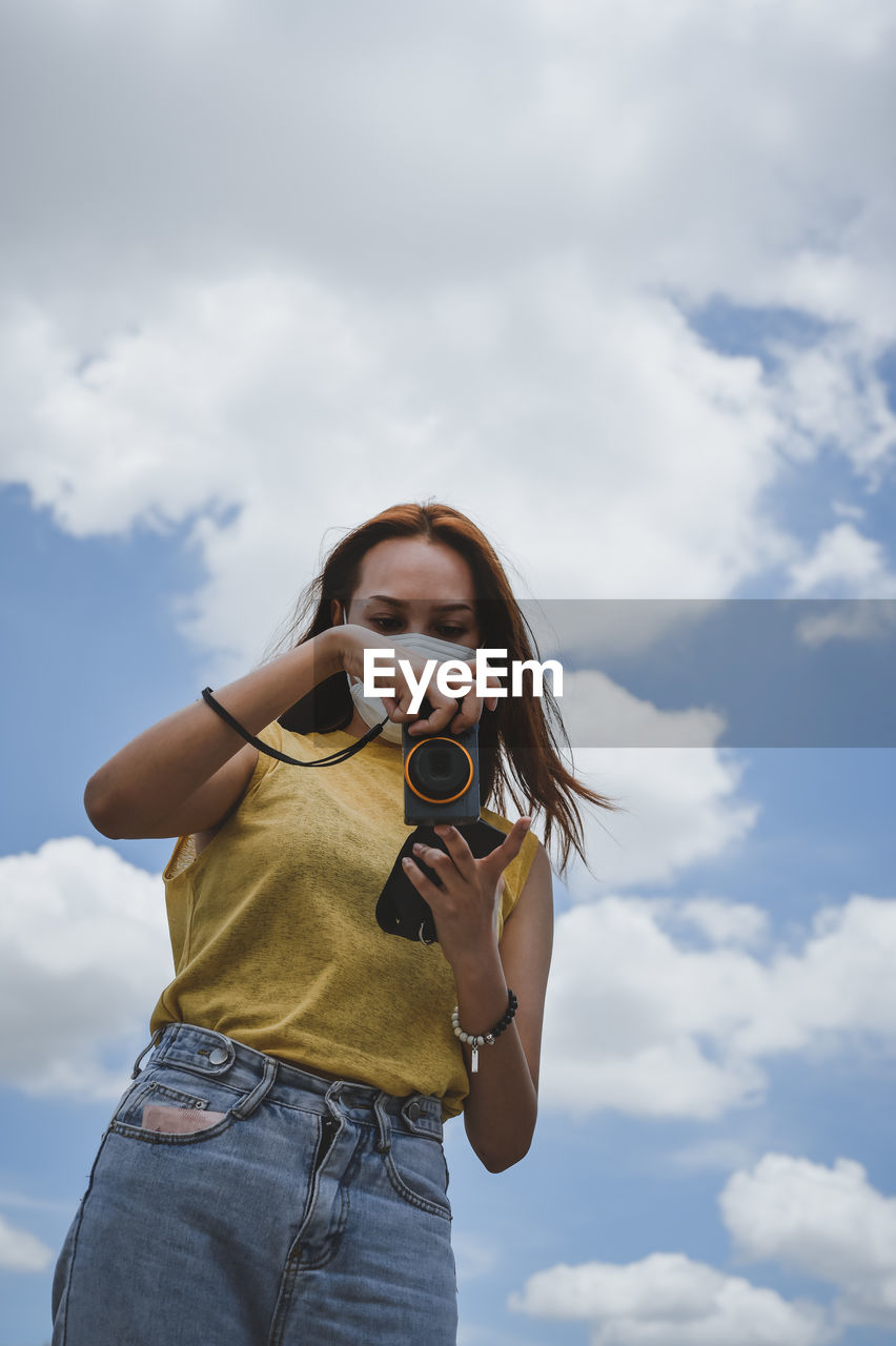 Young woman traveller using her camera ,beautiful cloud and sky in backgroung