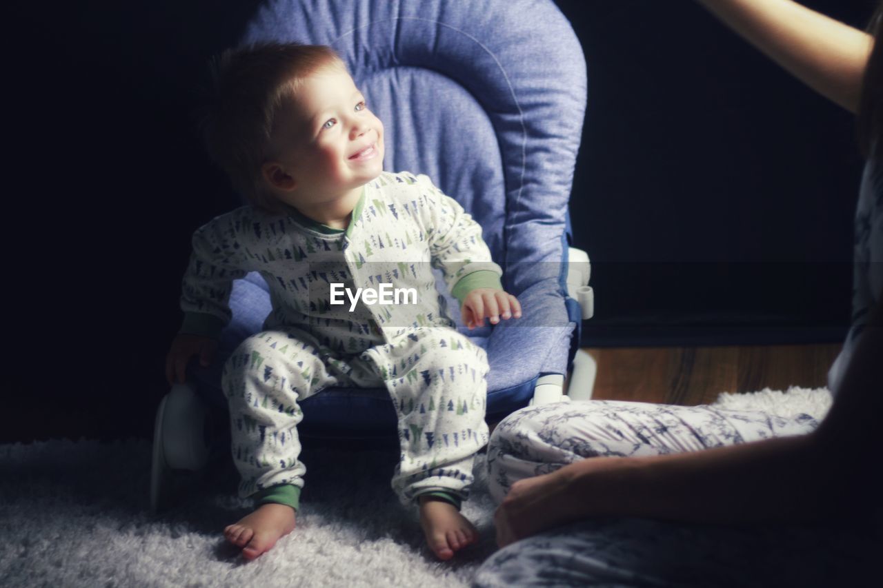 Full length of cute blonde baby in pajama on chair