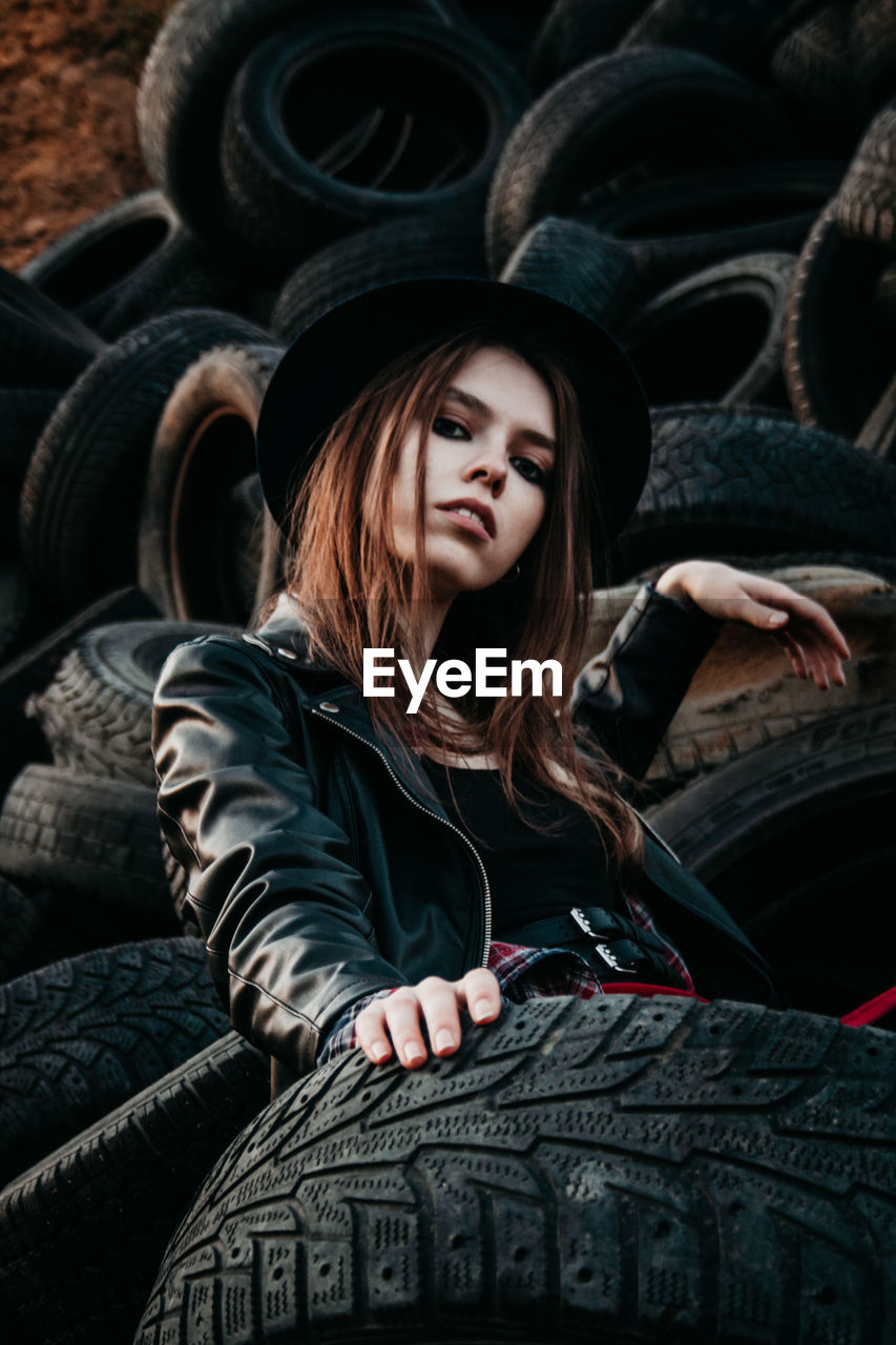 Portrait of young woman sitting on tires