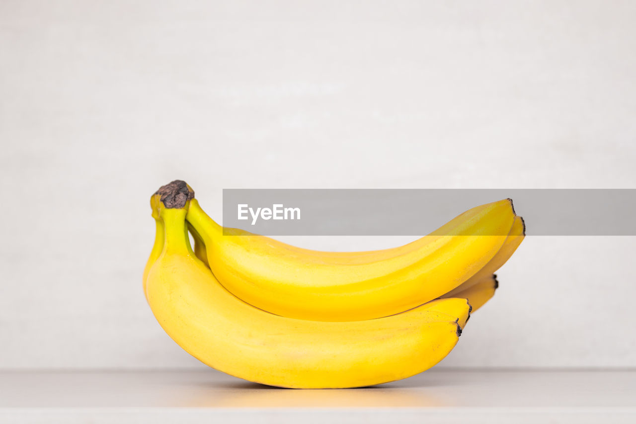A bunch of yellow ripe bananas on a gray background with a copy space