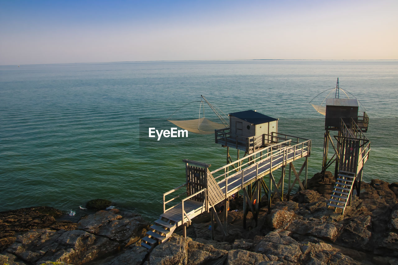 Scenic view of sea and fishing hut against sky