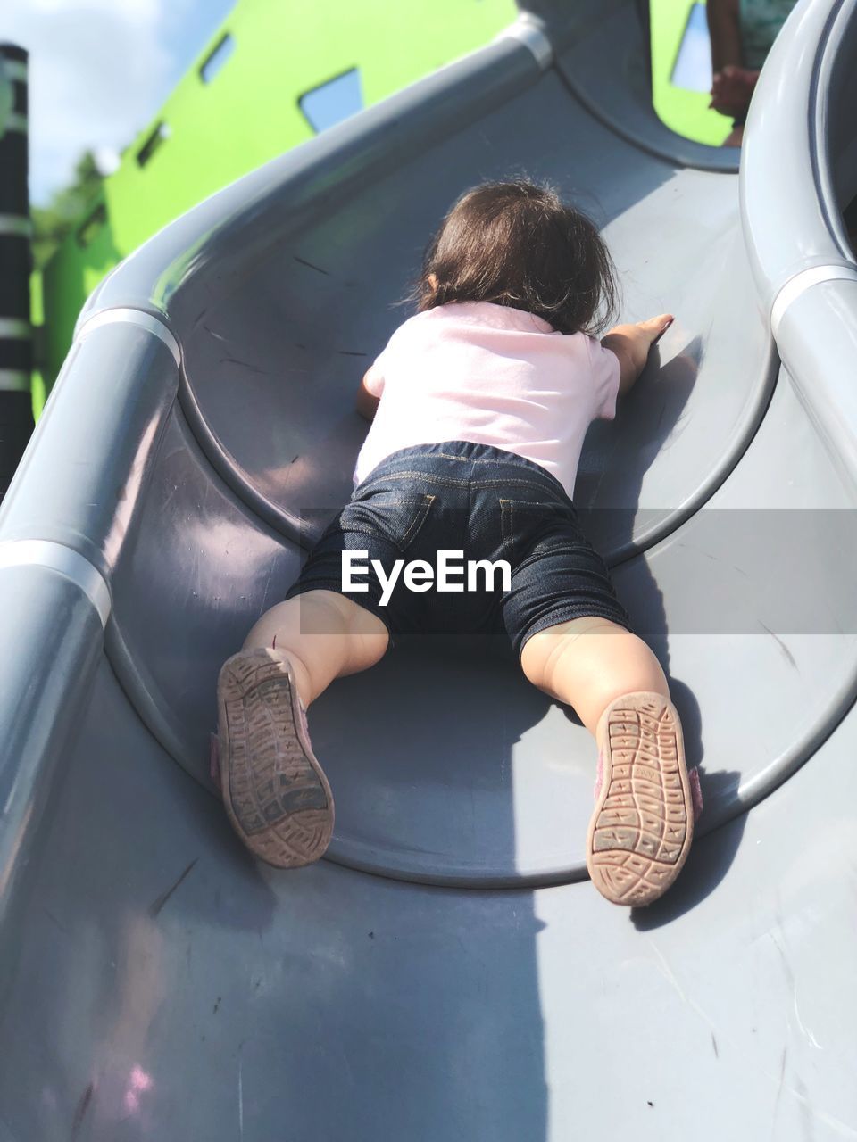 Low angle view of baby girl on slide at playground