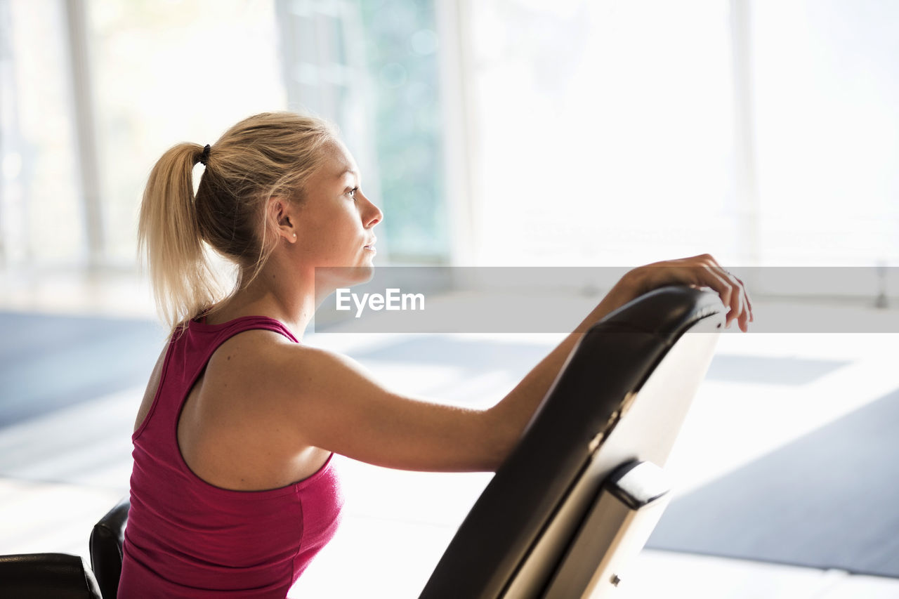 Young woman sitting on chair at gym