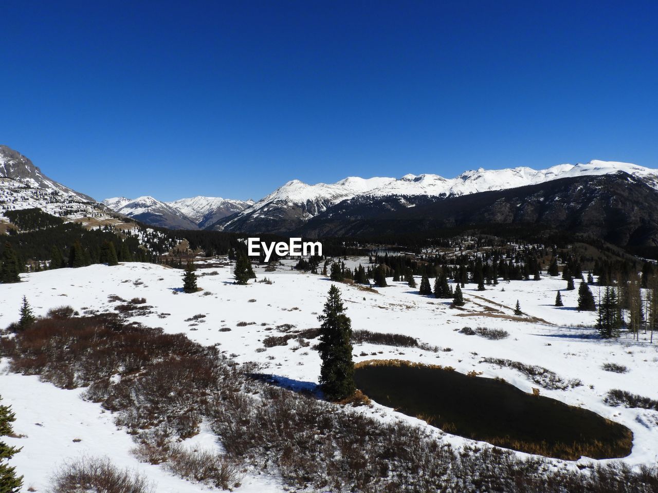 Scenic view of snow covered mountains against blue sky