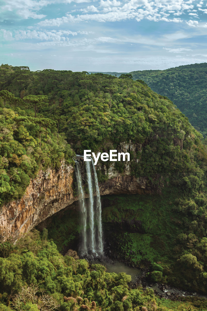 Caracol waterfall falling from rocky cliff in a canyon covered by forest near canela, brazil.