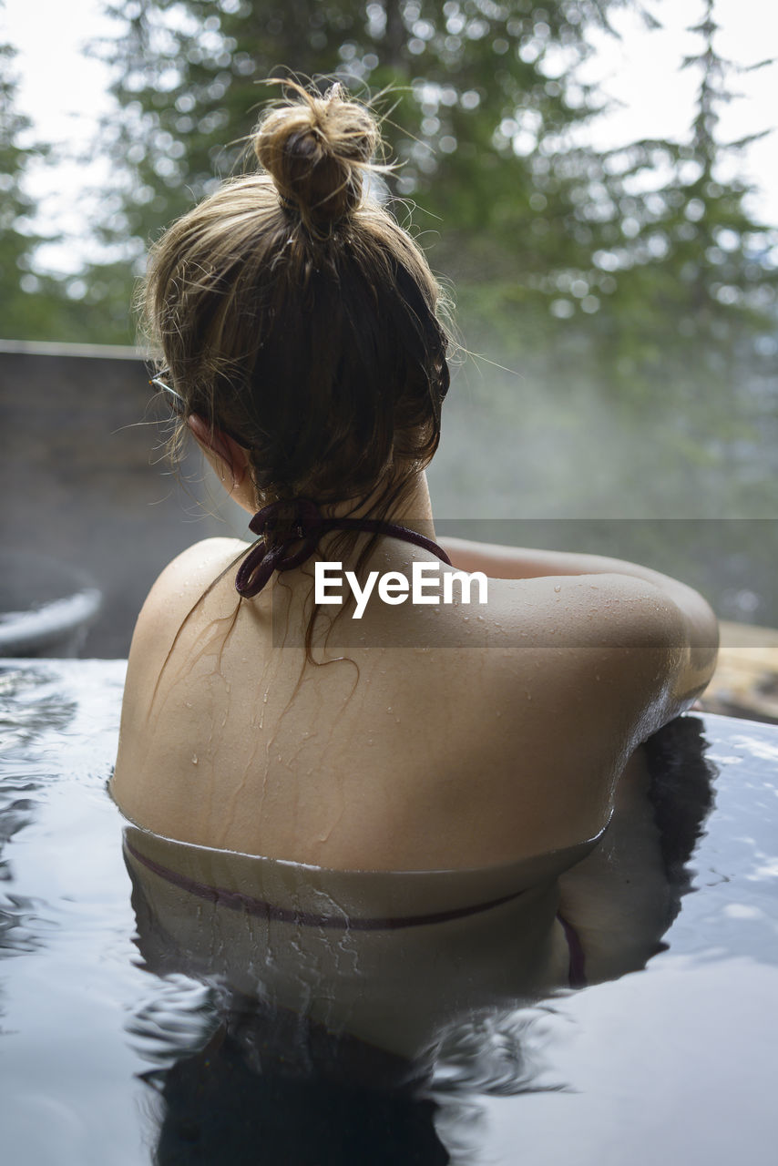 Rear view of woman relaxing in hot spring