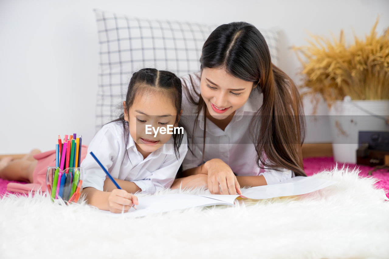 Mother helping daughter in doing homework at home