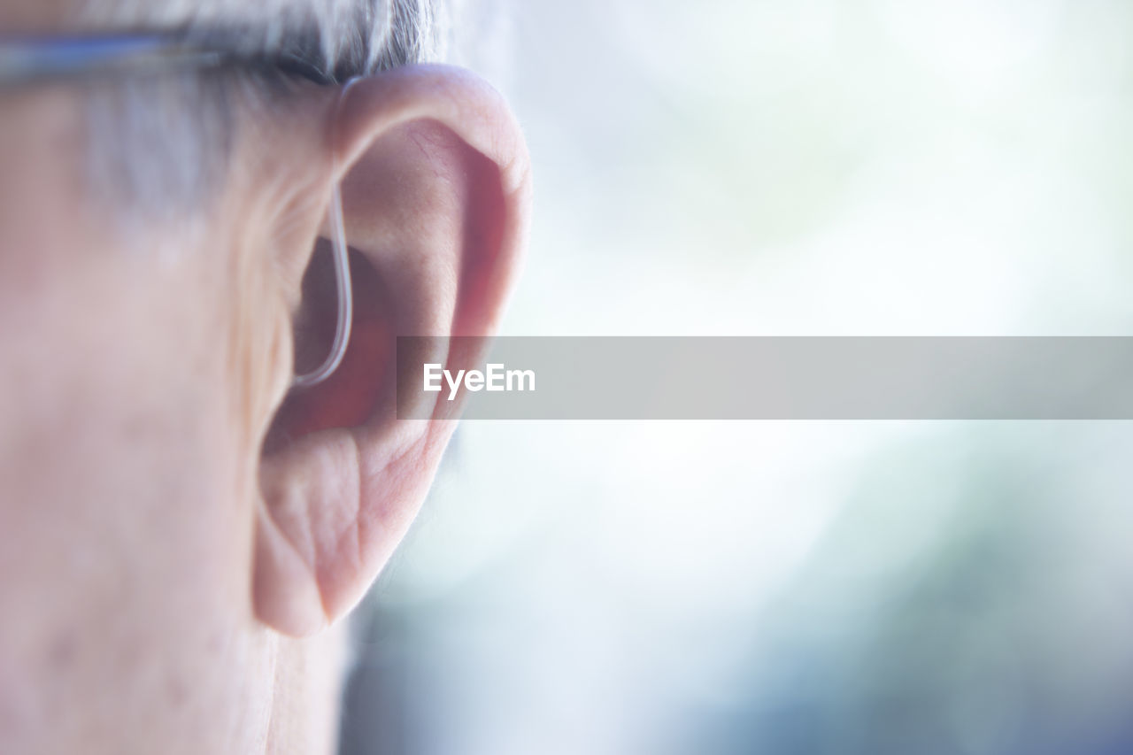 Close-up of man with hearing aid against blurred background