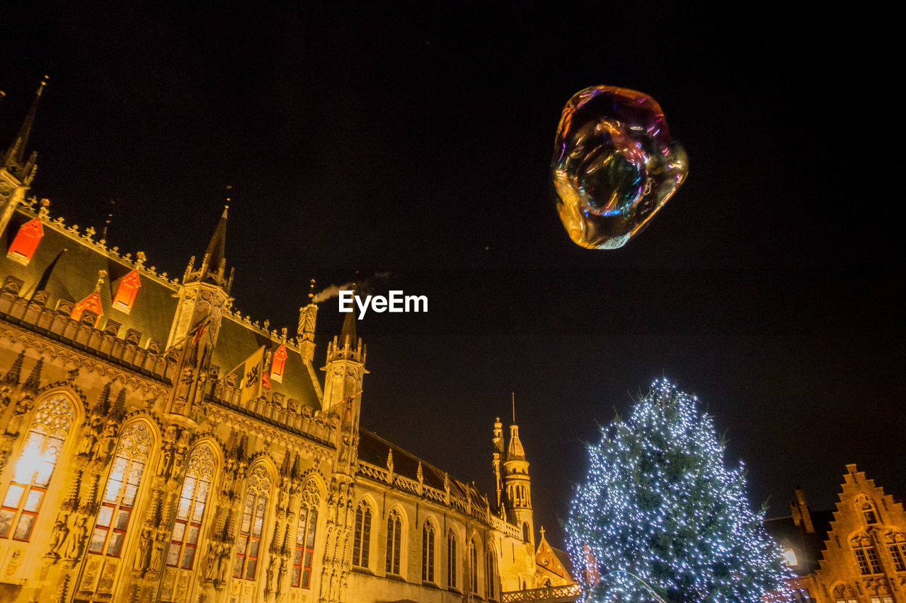 LOW ANGLE VIEW OF ILLUMINATED CHRISTMAS LIGHTS IN CITY