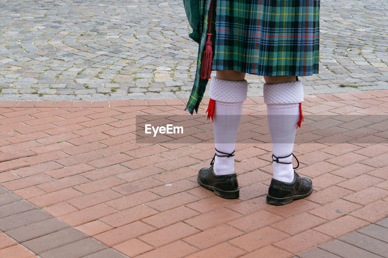 Low section of person in traditional clothing standing on footpath