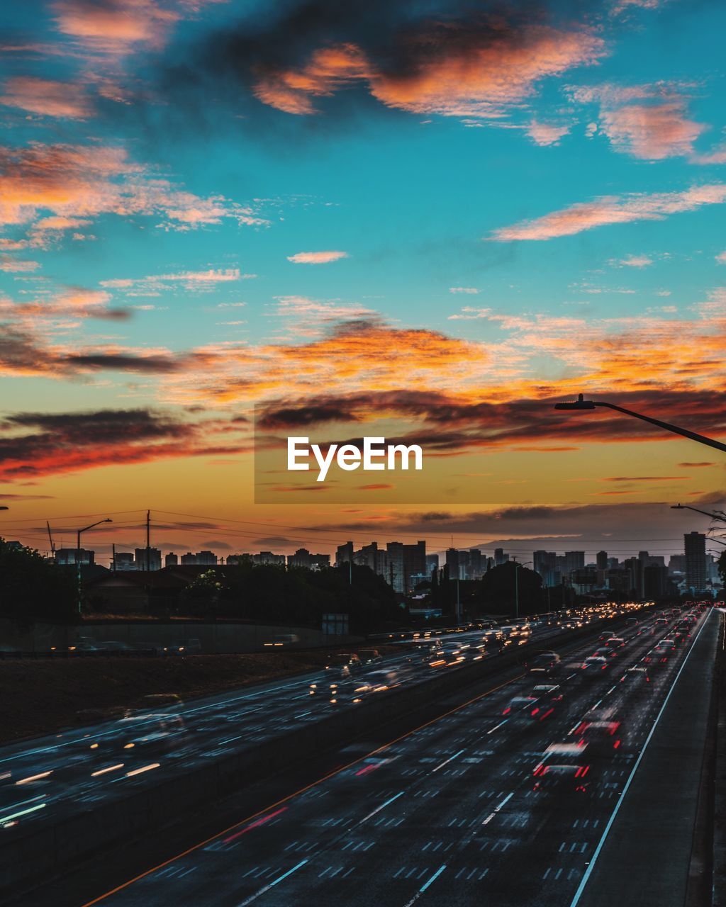 CARS MOVING ON ROAD AT SUNSET